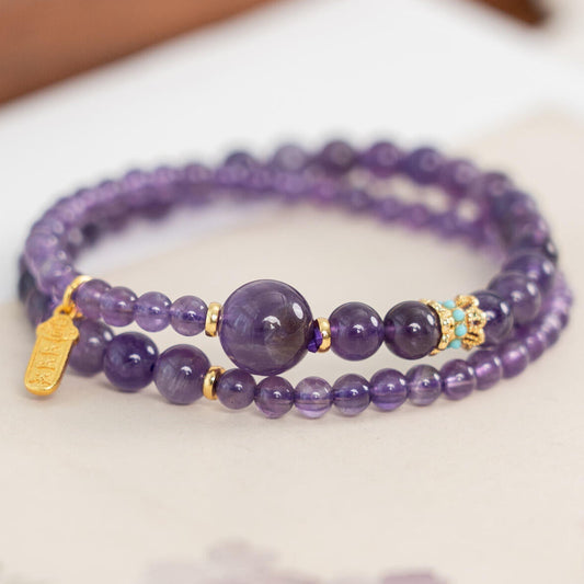 Genuine deep purple Amethyst 2-wrap mala bracelet featuring a gold amulet charm and turquoise accent bead close up