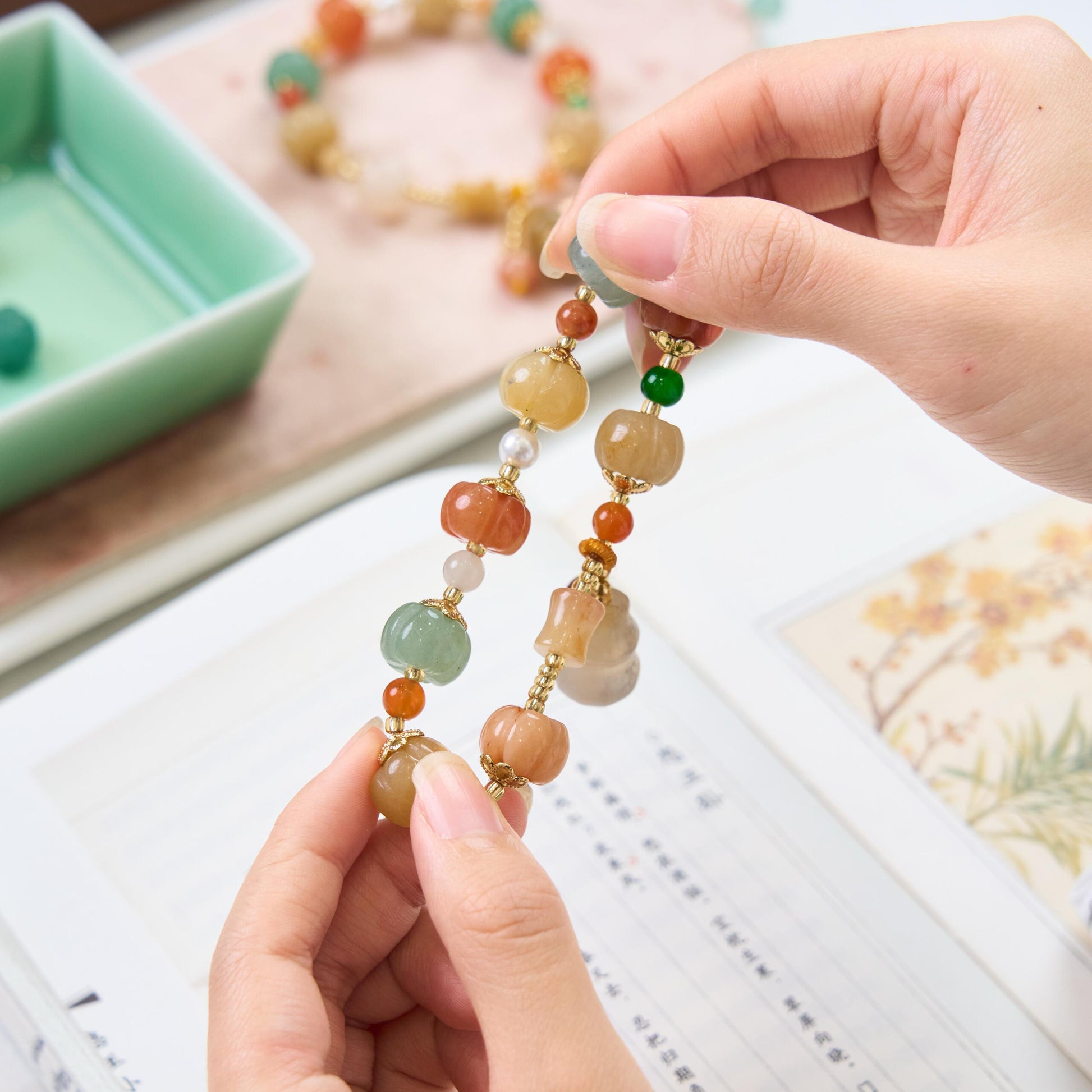 Close up of hand holding carved pumpkin jade beads showing the warm yellow and green natural stone texture