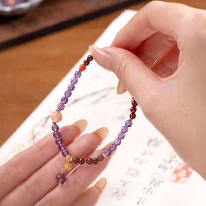 Fingers holding up Amethyst and Red Agate bracelet showing the natural translucency and petite bead size