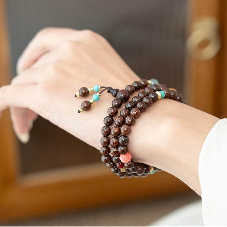 Woman wearing triple wrap Red Sandalwood bracelet with carved Mother-of-Pearl lotus bead and turquoise tassel