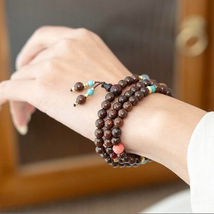 Woman wearing triple wrap Red Sandalwood bracelet with carved Mother-of-Pearl lotus bead and turquoise tassel