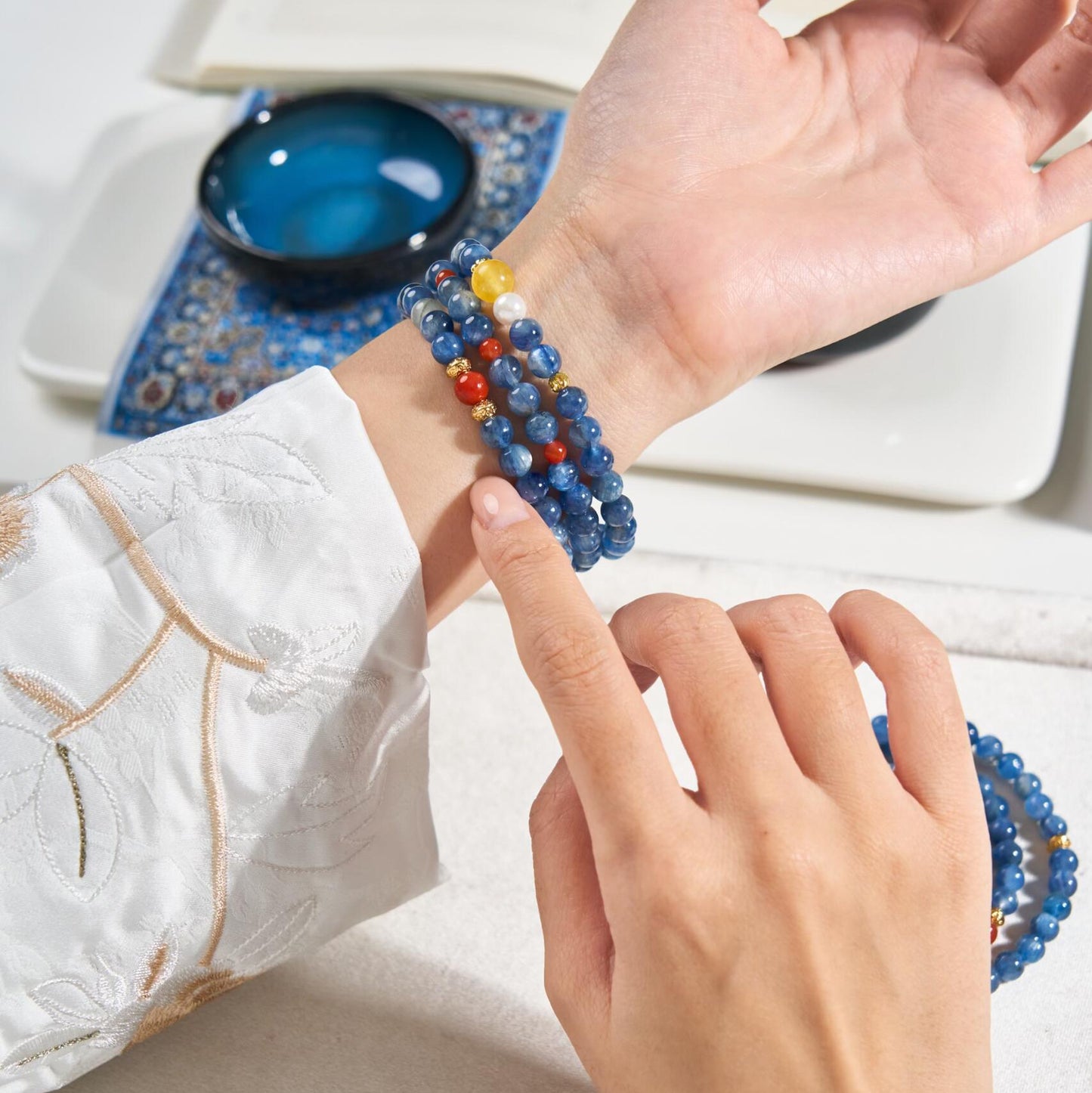 Woman wearing three stacked blue Kyanite bracelets on wrist, showing the beautiful layered gemstone effect
